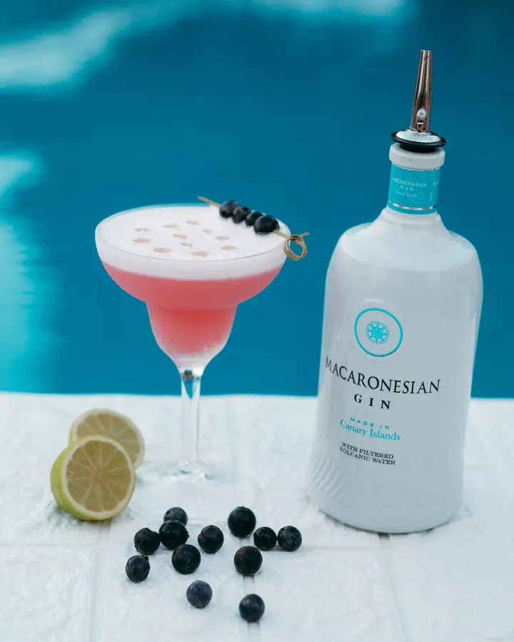 A pink cocktail next to a bottle of Macaronesian gin